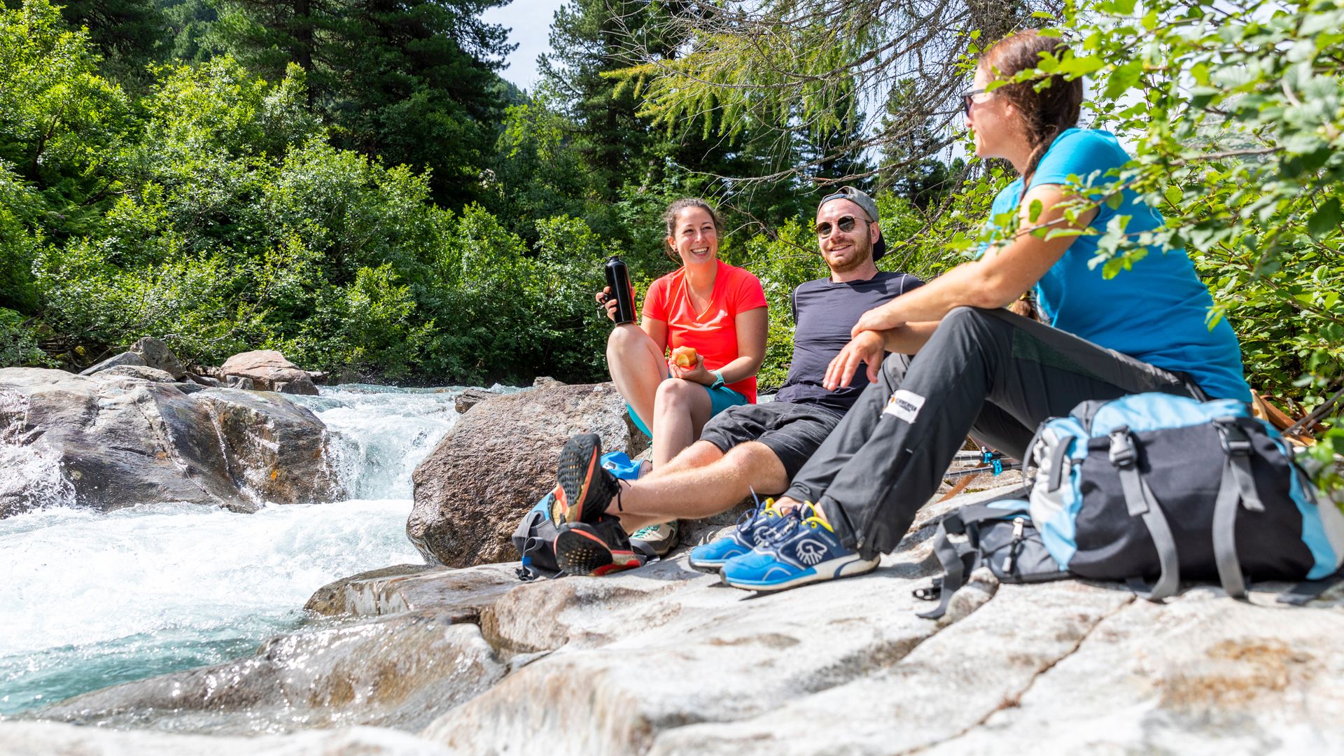 Participants of a guided hike in the Zillertal Alps Nature Park take a break by a mountain stream. Surrounded by pristine nature and fresh alpine air, they experience the Mayrhofen-Hippach holiday region actively. A perfect mix of nature and community.