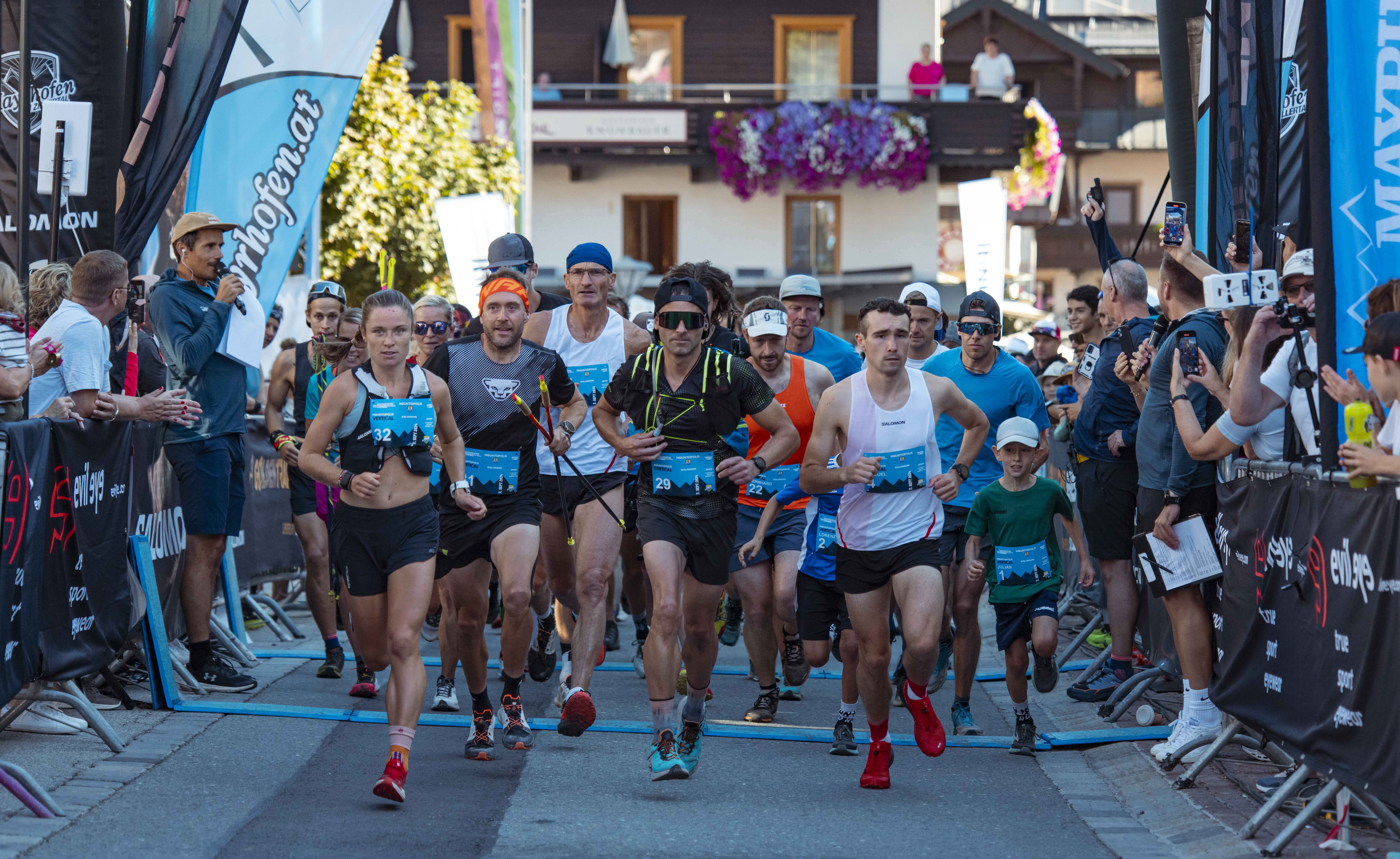 Läufer starten beim Mayrhofen Ultraks, umgeben von Zuschauern und bunten Bannern in einem alpinen Dorf.