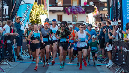 Läufer starten beim Mayrhofen Ultraks, umgeben von Zuschauern und bunten Bannern in einem alpinen Dorf.