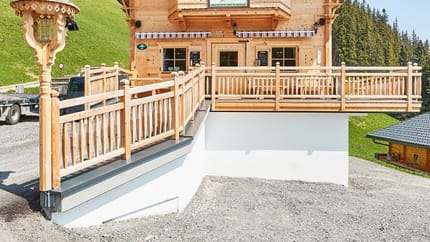 The picture shows the Nasenalm snack station in summer with a meadow and a forest in the background.