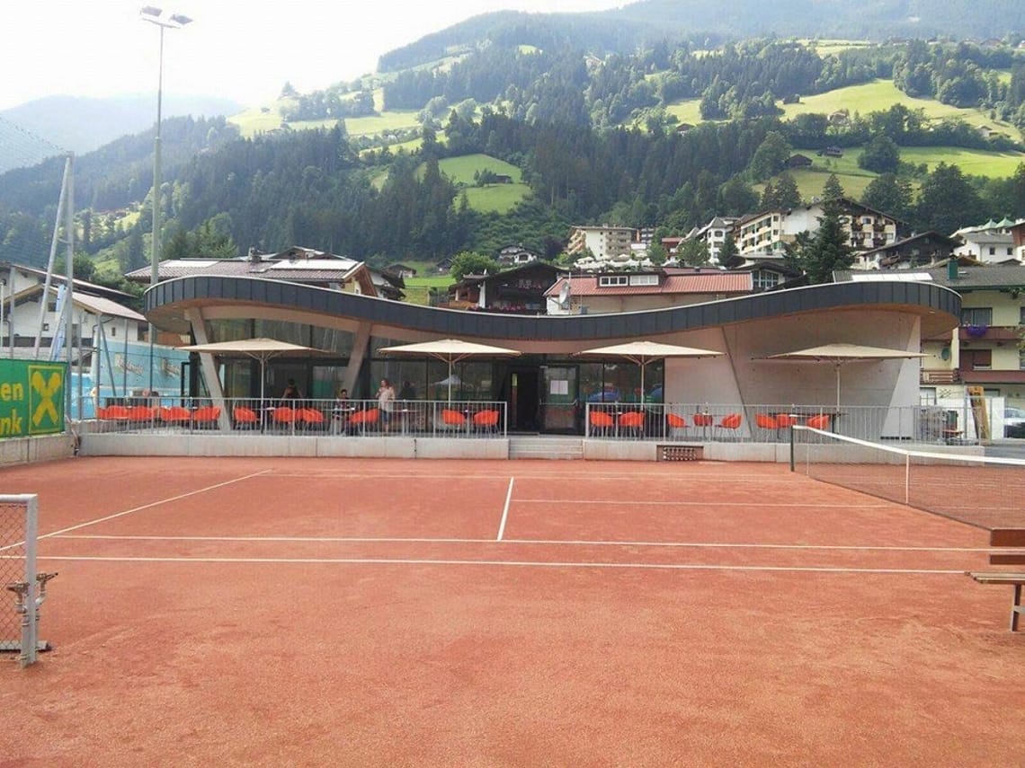 Tenniscourt of the TC Raiffeisen Hippach Clay tennis court at Sommerwelt Hippach with a modern clubhouse and scenic view of the Zillertal Alps – perfect for playing tennis in Tyrol.