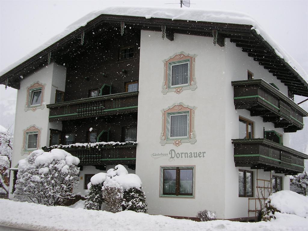 Mehrstöckiges Gasthaus 'Dornauer' im Schnee mit Balkonen und verschneiten Büschen im Vordergrund.