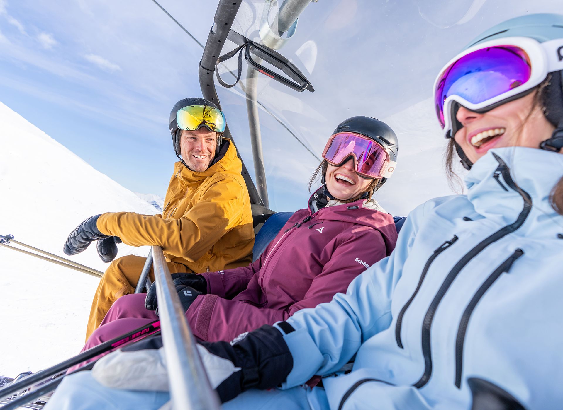 Freunde sitzen am Lift und lachen bei Sonnenschein