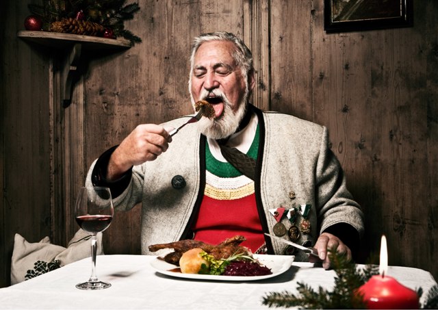 Das Bild zeigt einen Mann in traditioneller Zillertaler Tracht, der in einer gemütlichen, alten Stube isst. Vor ihm steht ein Glas Rotwein, und eine rote Kerze sorgt für warmes, stimmungsvolles Licht.