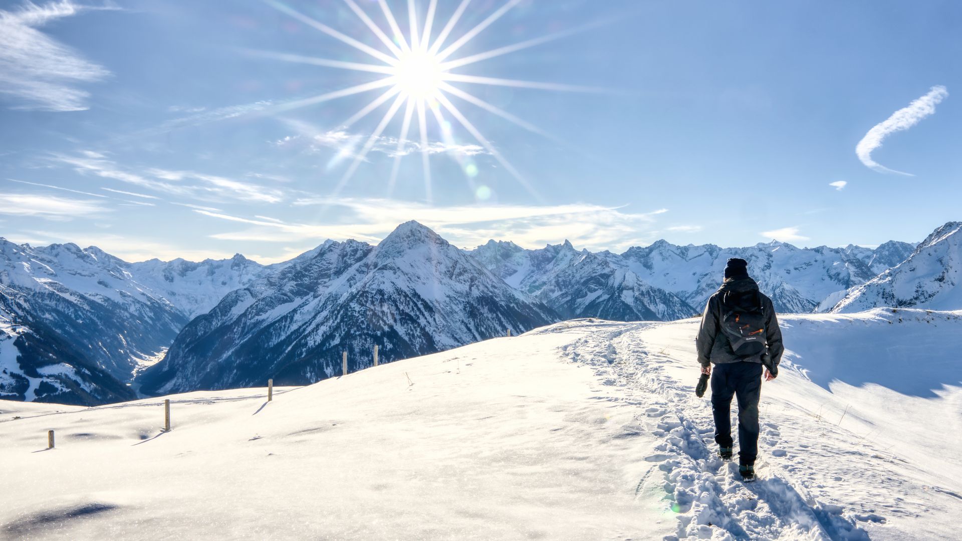 Wintertraum in Mayrhofen-Hippach In einer verschneiten Bergwelt ist eine Dame bei strahlendem Sonnenschein unterwegs. Die Dame sieht man von hinten, wie sie den bereits vorhandenen Spuren im Schnee folgt.Spuren im Schnee  von hinten sieht