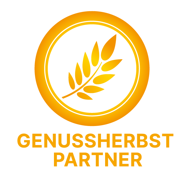 Logo „Genussherbst Partner“ in Goldgelb. Das kreisförmige Emblem zeigt eine Getreideähre in der Mitte. Darunter steht in Großbuchstaben der Schriftzug GENUSSHERBST PARTNER auf weißem Hintergrund.