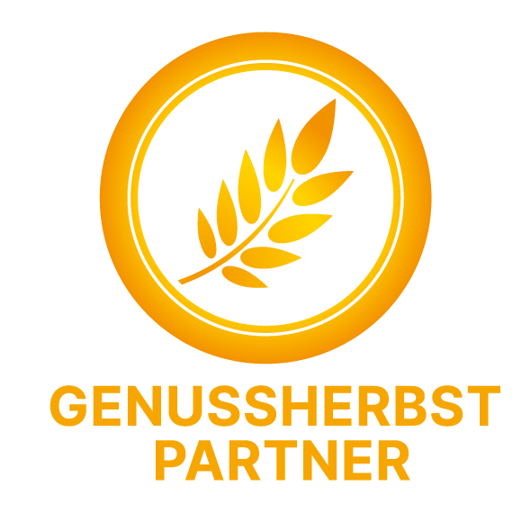 Logo „Genussherbst Partner“ in Goldgelb. Das kreisförmige Emblem zeigt eine Getreideähre in der Mitte. Darunter steht in Großbuchstaben der Schriftzug GENUSSHERBST PARTNER auf weißem Hintergrund.