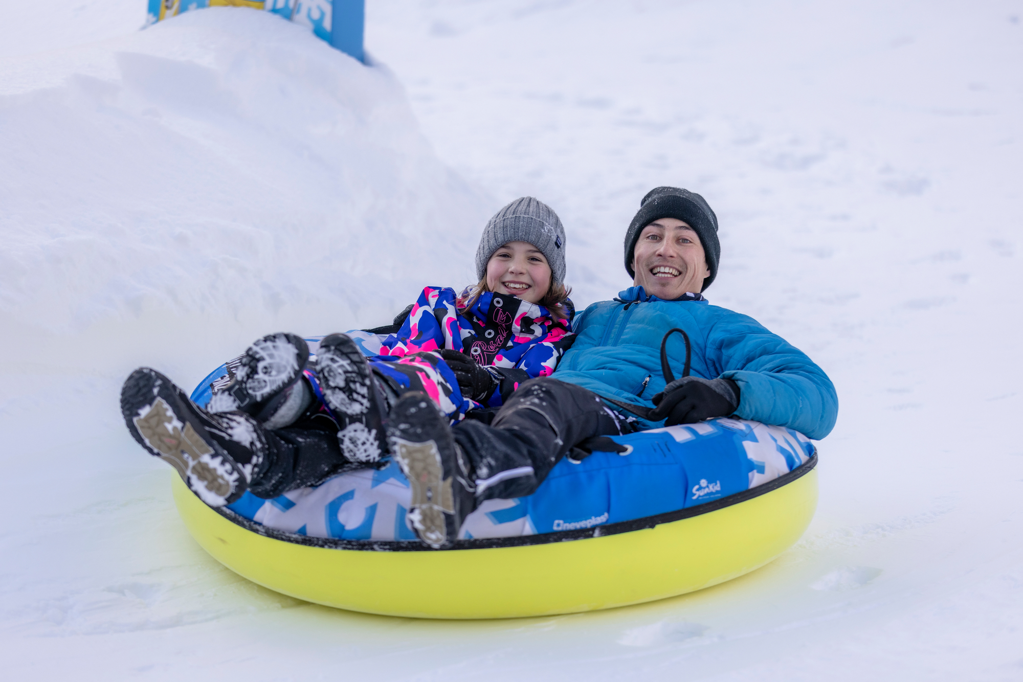 Adult and child laughing while snowtubing at Winterzauber Ginzling in the Zillertal Valley