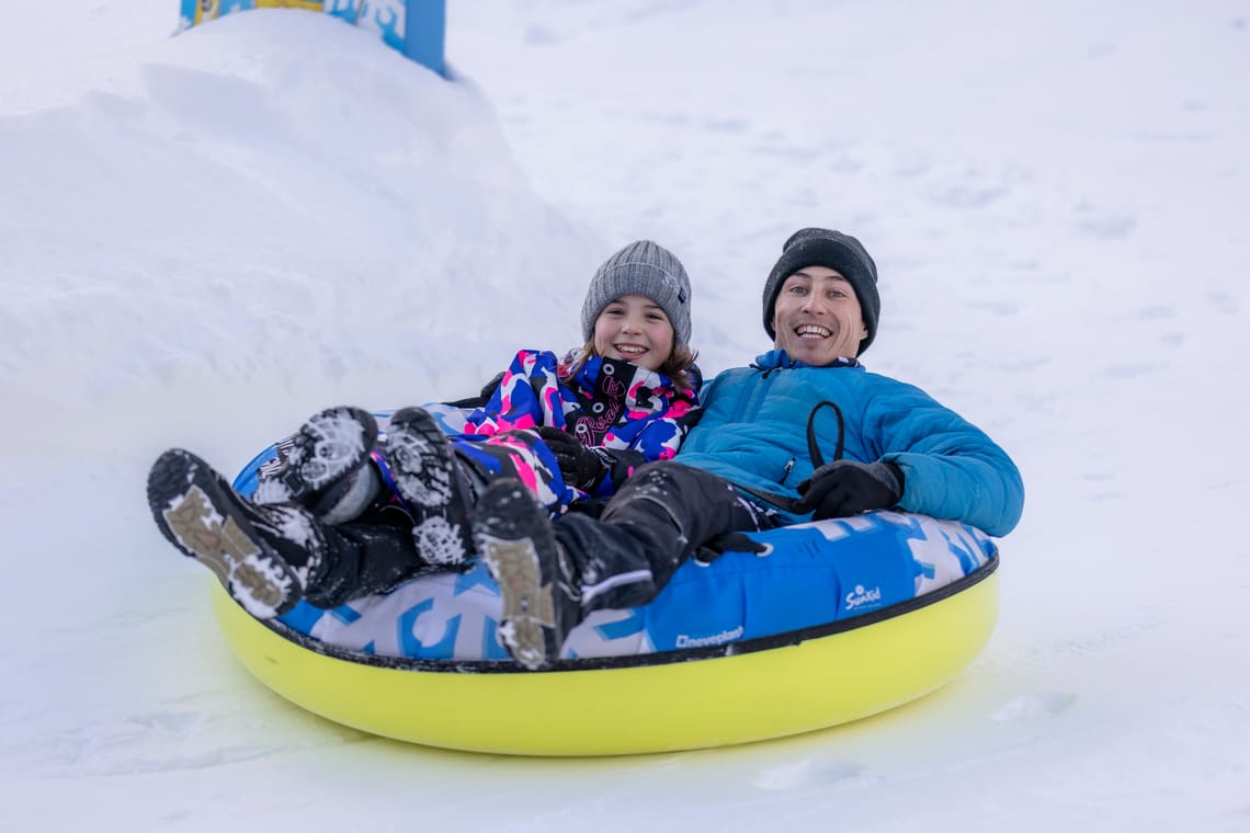 Man and child snowtubing in Ginzling