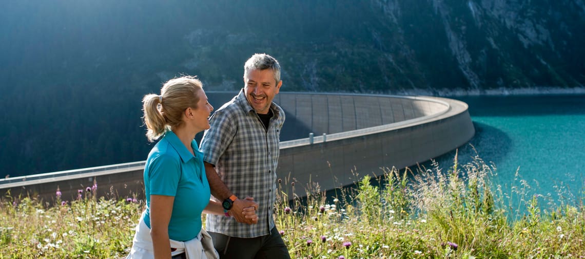 Menschen beim Spaziergang vor einer Staumauer