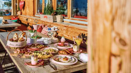 Ein Frühstückstisch auf der Terrasse mit verschiedenen Spreisen (Eier, Joghurt, Brot)