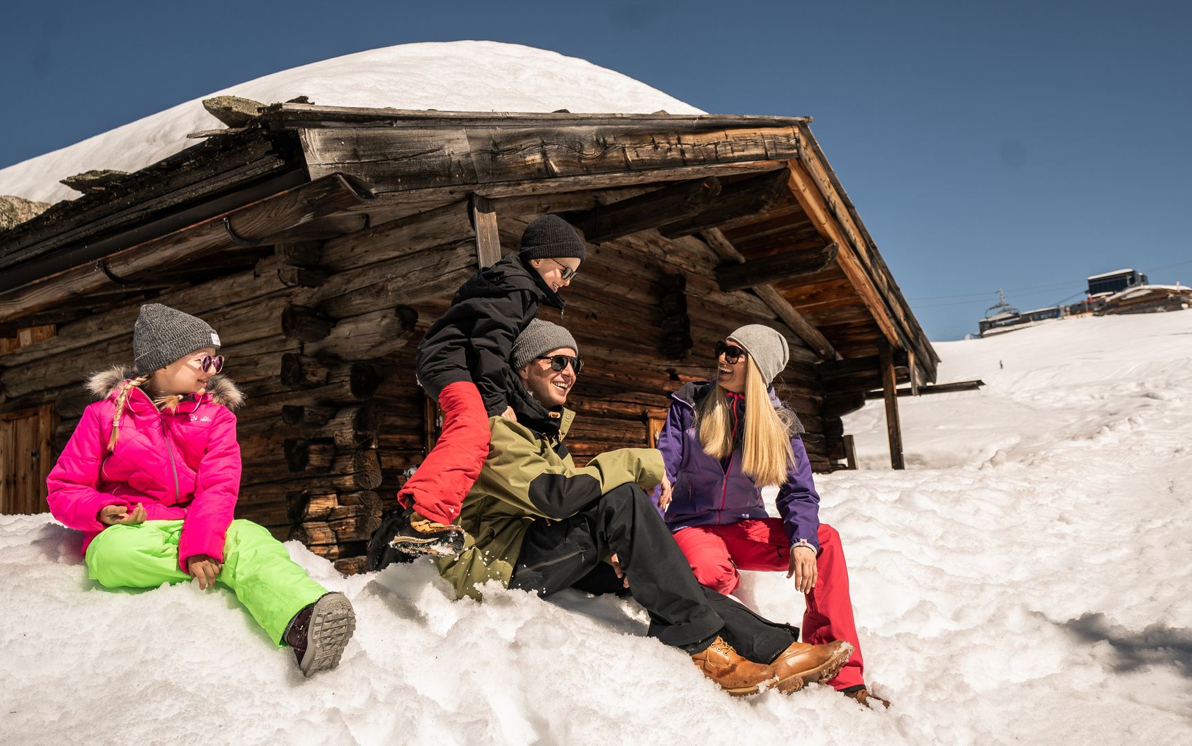 Familie vor einer Hütte im Skigebiet Ahorn