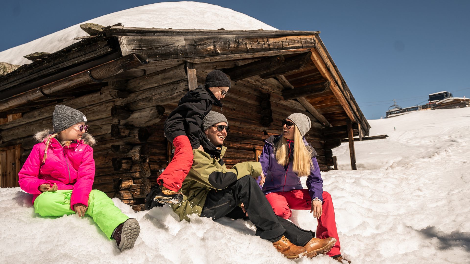 Familie vor einer Hütte im Skigebiet Ahorn