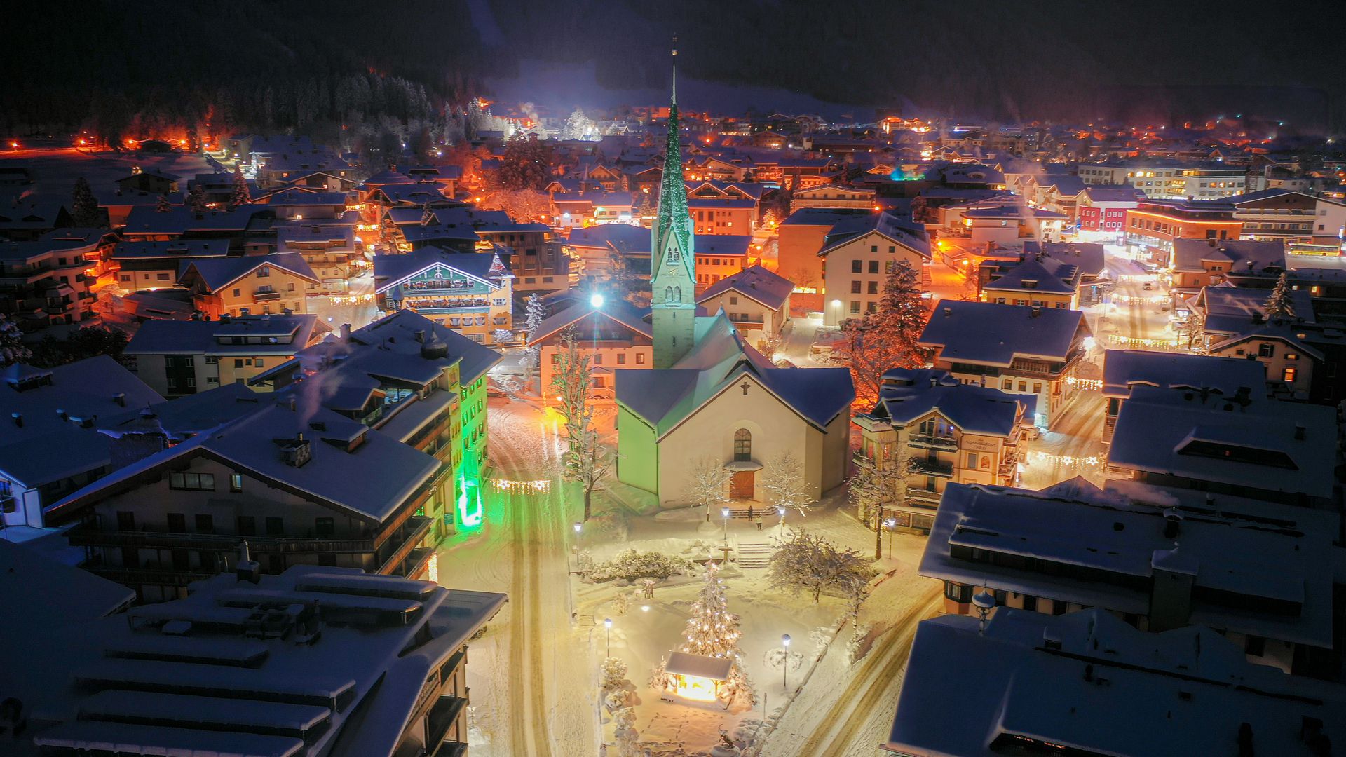 Mayrhofner Advent Calendar - 4 Mountain Moments Snow-covered mountain landscape in Mayrhofen-Hippach under clear skies, snow-covered roofs in the foreground, ski lifts and slopes visible, scattered trees, tranquil winter atmosphere.