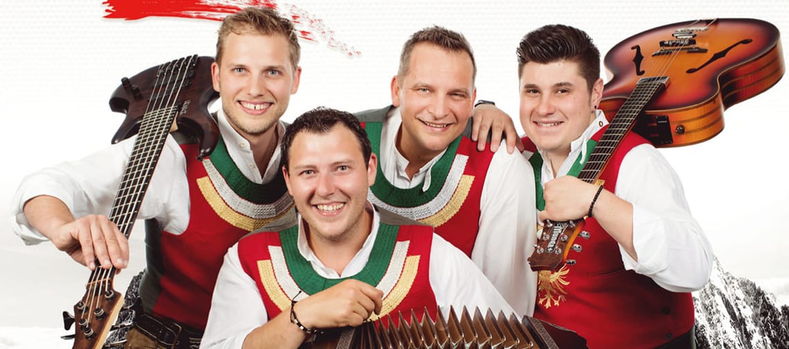 Vier Männer in traditioneller Kleidung mit Instrumenten, vor Bergkulisse, werben für Z-Pur Tiroler Volksmusik.