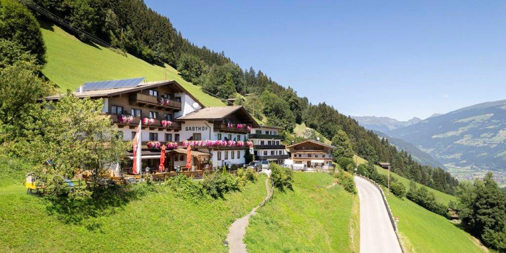 Gasthof Berghof am Schwendberg bei Mayrhofen-Hippach: traditionelles Gasthaus in sonniger Hanglage, umgeben von Wiesen und Bergen – Genussherbst-Partnerbetrieb für die Kulinarischen Genussherbst Wochen.