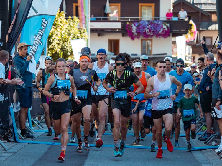 Start des Mayrhofen Ultraks Zillertal: Trailrunner starten im Ortszentrum von Mayrhofen unter dem Startbogen, begleitet von zahlreichen Zuschauern entlang der Strecke.