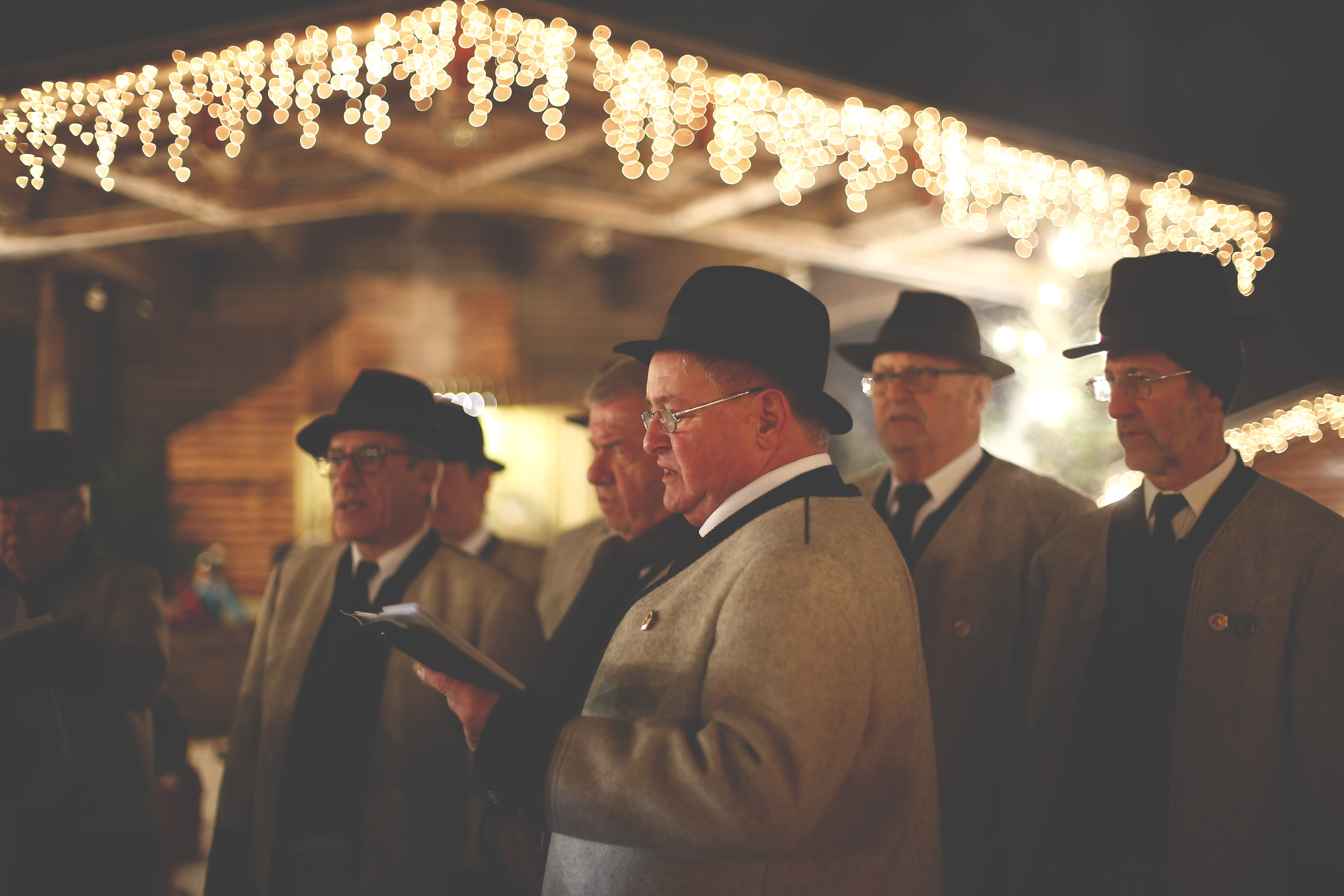 The picture shows the Men’s Choir Association of Mayrhofen singing in front of an illuminated stage at the Mayrhofen Advent event.