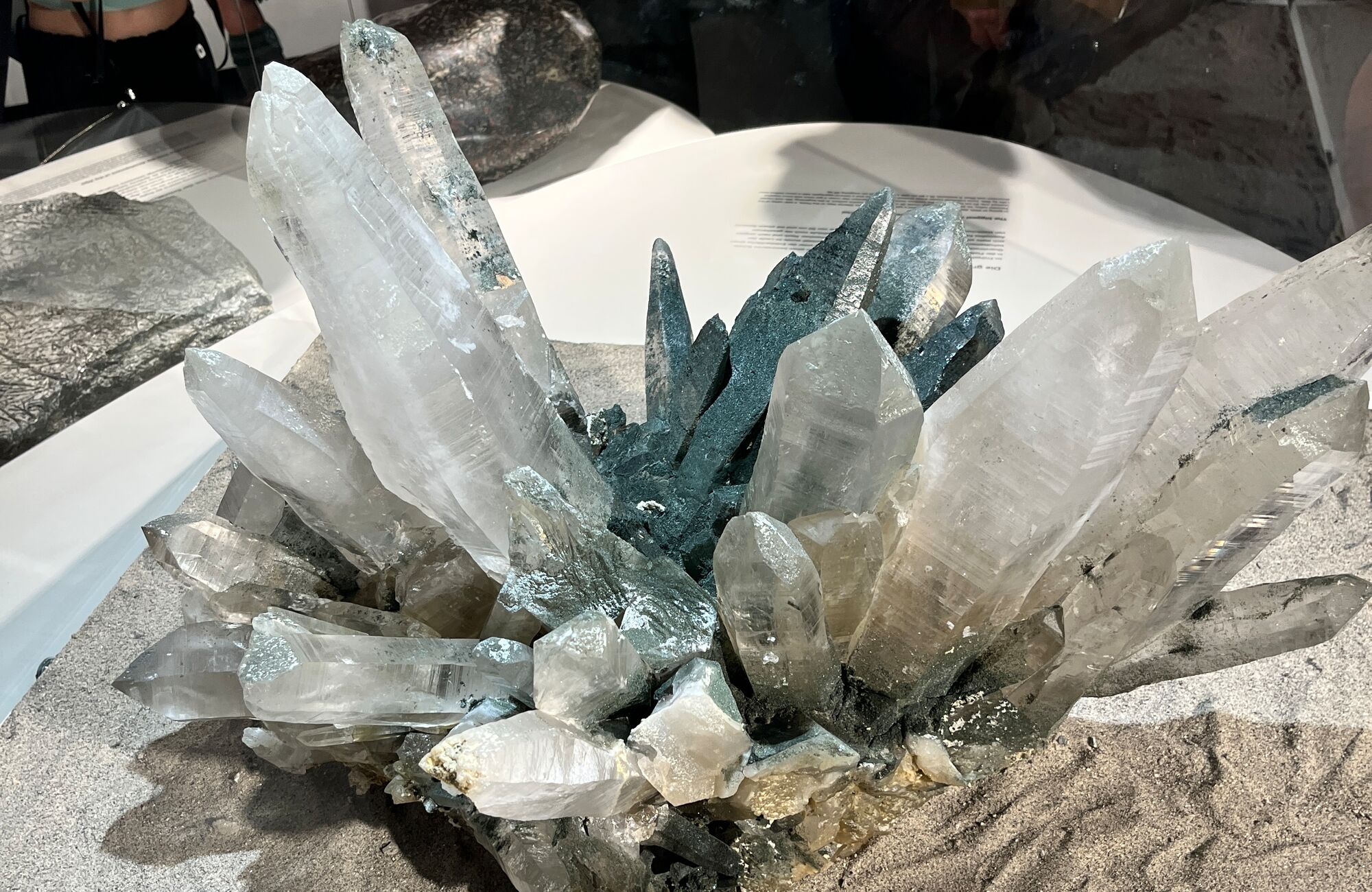 Close-up of an impressive rock crystal formation in the "Hidden Treasures" exhibition at the Ginzling Nature Park House. The clear and shimmering crystals emerge from a rocky base.