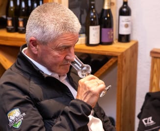 Brennmeister verkostet konzentriert den HIPPSTAR-Edelbrand am Glas, im Hintergrund Flaschenregal in der Stube.