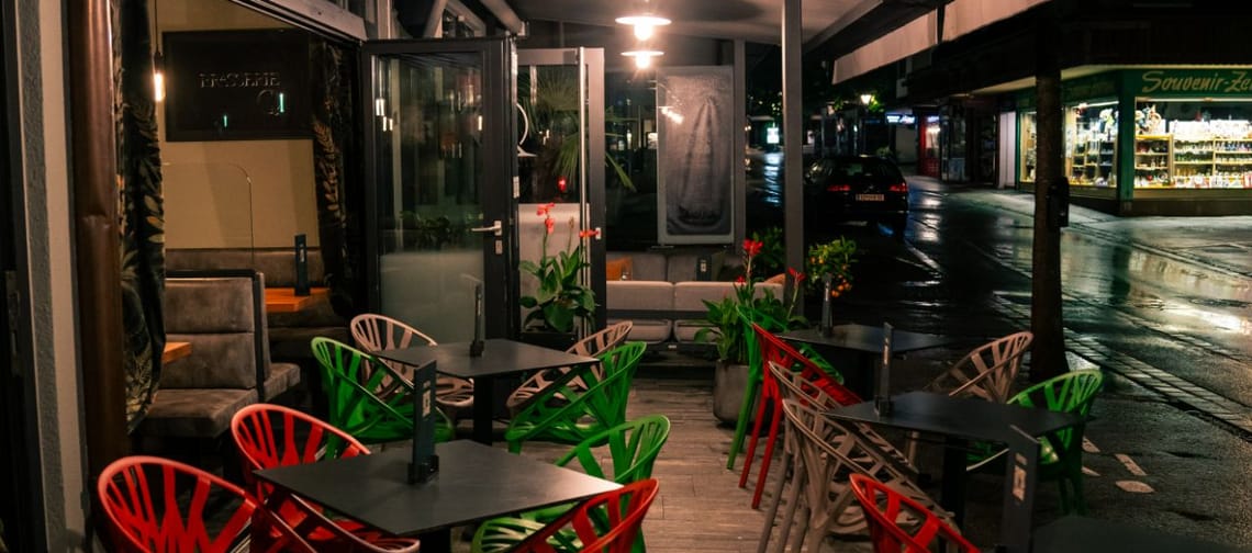 Das Logo der Brasserie Q hat einen weißen Hintergrund und eine dünne, elegante Schrift. Das „Q“ steht etwas größer und leicht versetzt unter dem restlichen Schriftzug, was dem Design eine stilvolle und moderne Note verleiht.