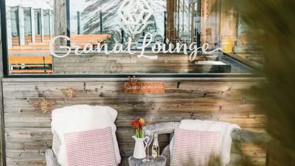 Das Bild zeigt eine Außenaufnahme der Granat Lounge mit Tischen und einer Bergkulisse im Hintergrund.