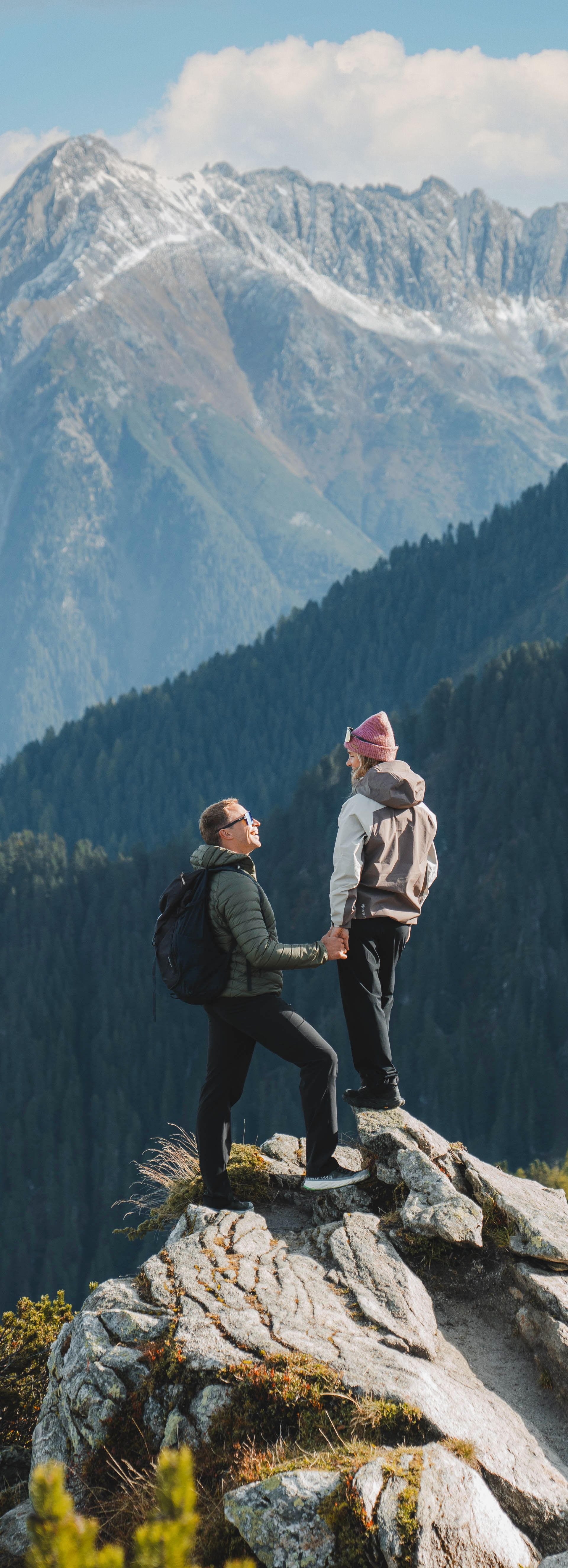 Paar steht auf Felsen und im Hintergrund die Berge