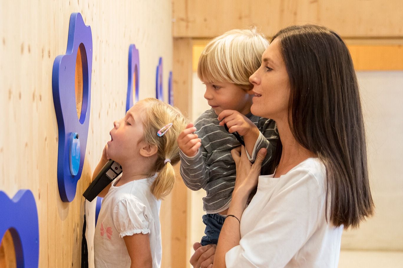Erlebnissennerei Zillertal Mutter mit zwei Kindern entdeckt interaktive Ausstellung in der Erlebnissennerei Zillertal in Mayrhofen – Familienausflug mit Blick hinter die Kulissen der Milch- und Käseproduktion.