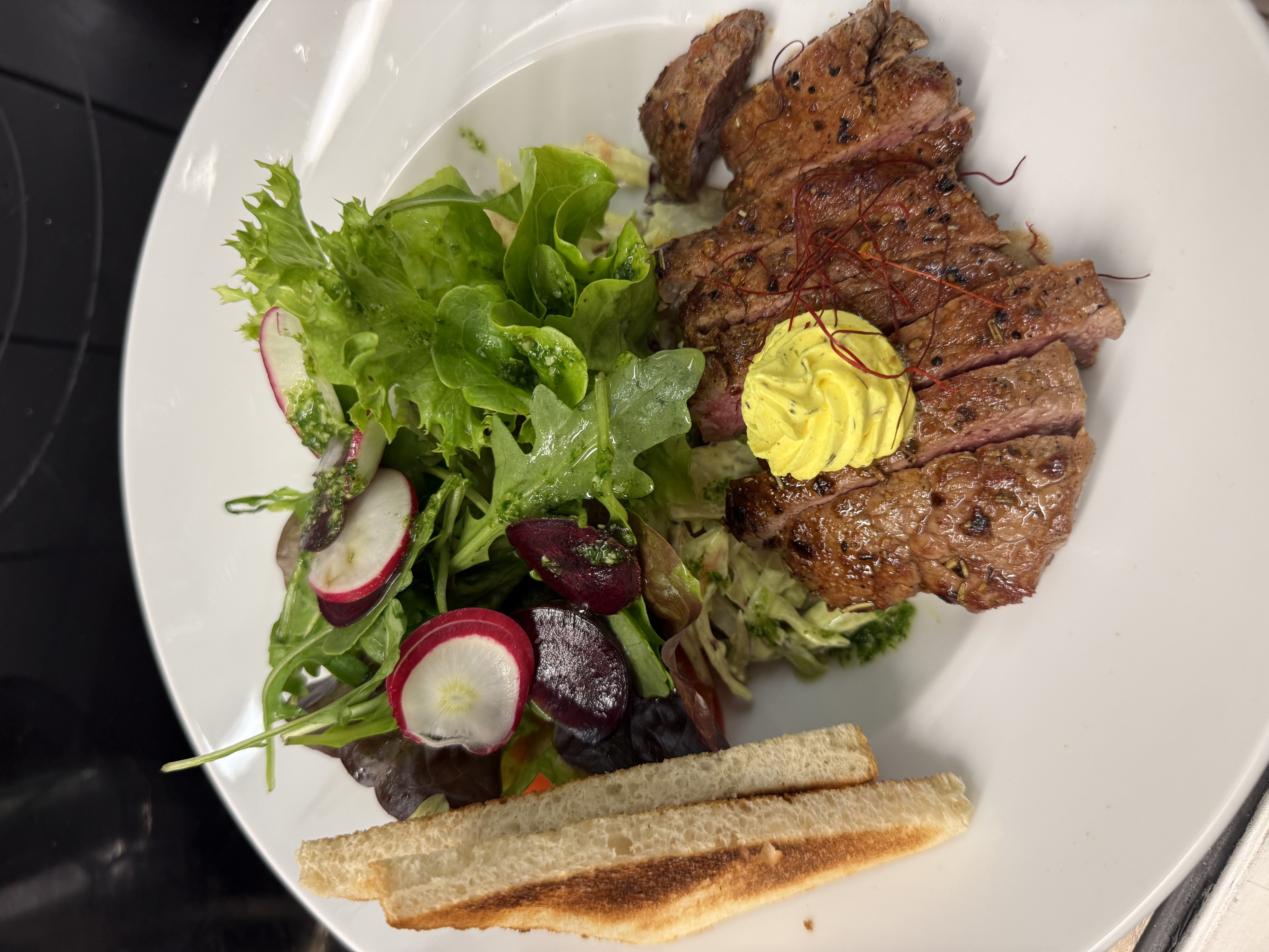 Teller mit Essen, Salat, Steak mit Kräuterbutter und frischem Salat