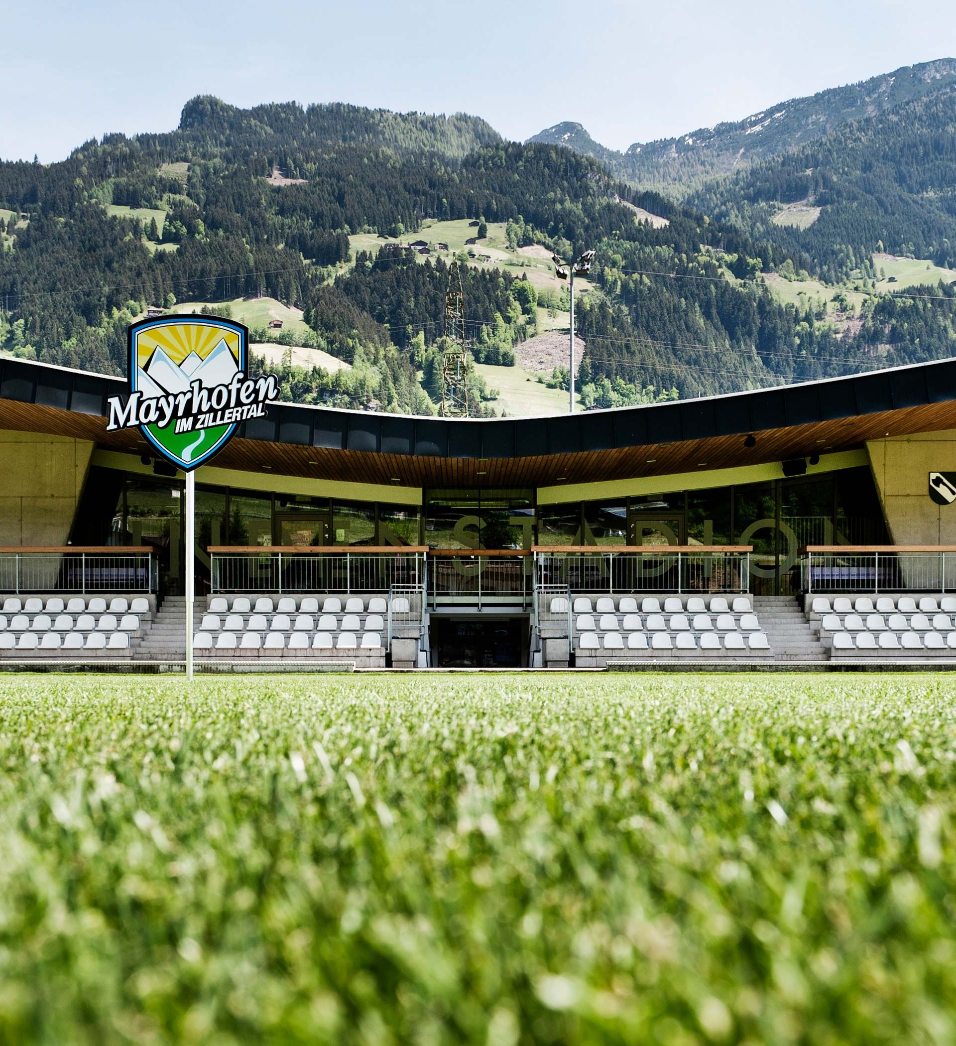 Lindenstadion football stadium in Hippach featuring modern timber architecture, seating stands, and a view of the green Alpine landscape; home ground of SK Hippach in Tyrol.