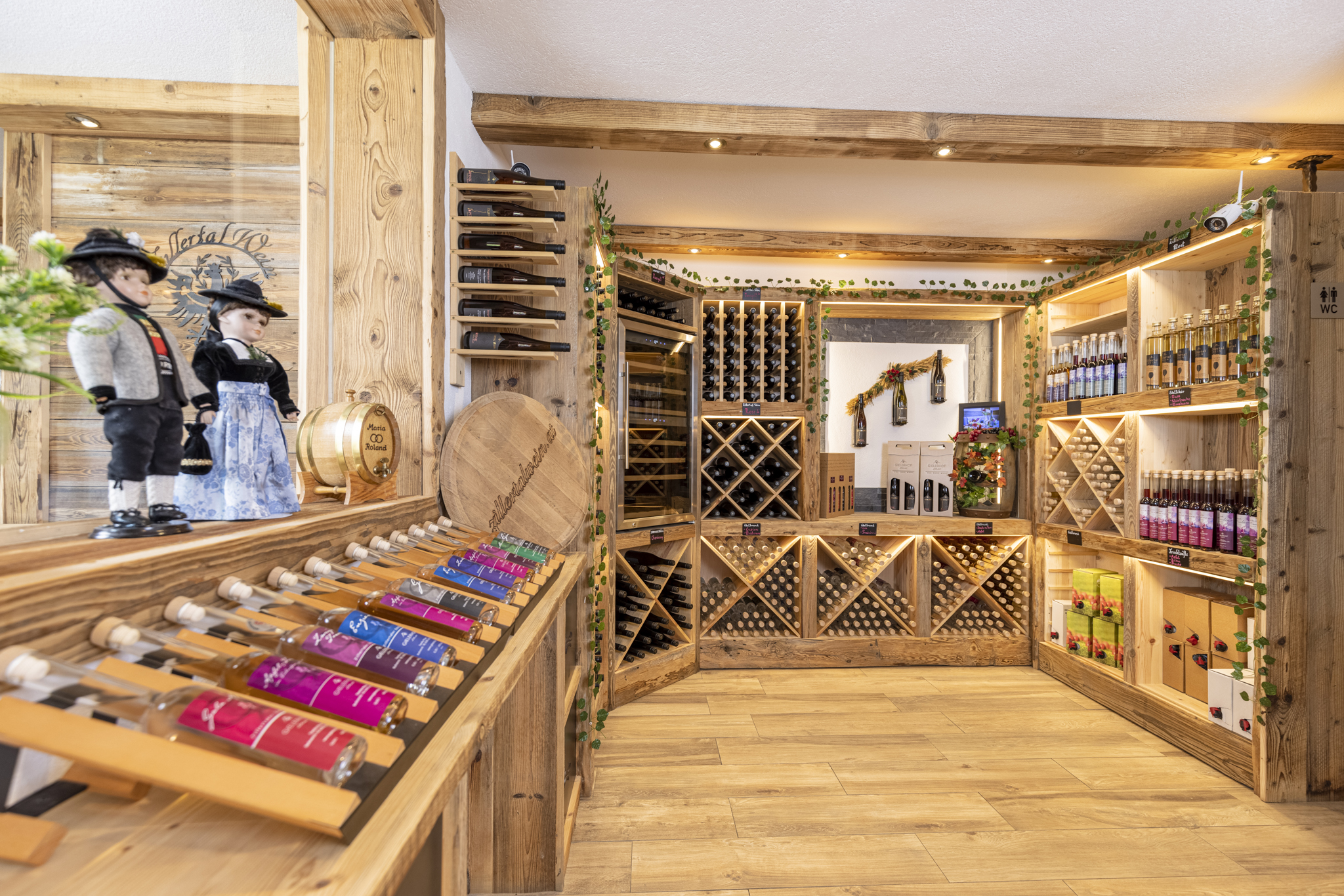 Interior of a wine shop with wooden shelves, wine bottles, decorations, and figurines in front.