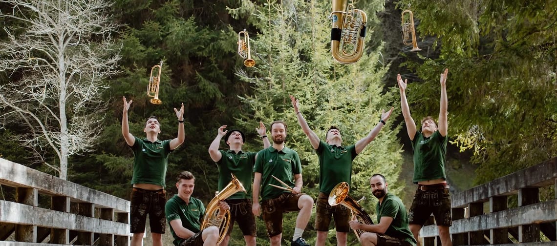 The picture shows the music group Turboländer on a bridge, tossing their instruments into the air and catching them for the photo.