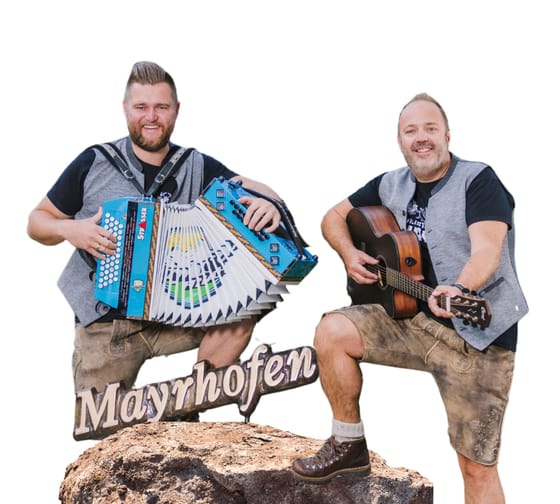 Zwei Männer spielen Musik, einer mit Akkordeon, der andere mit Gitarre, auf einem Felsen im Freien.