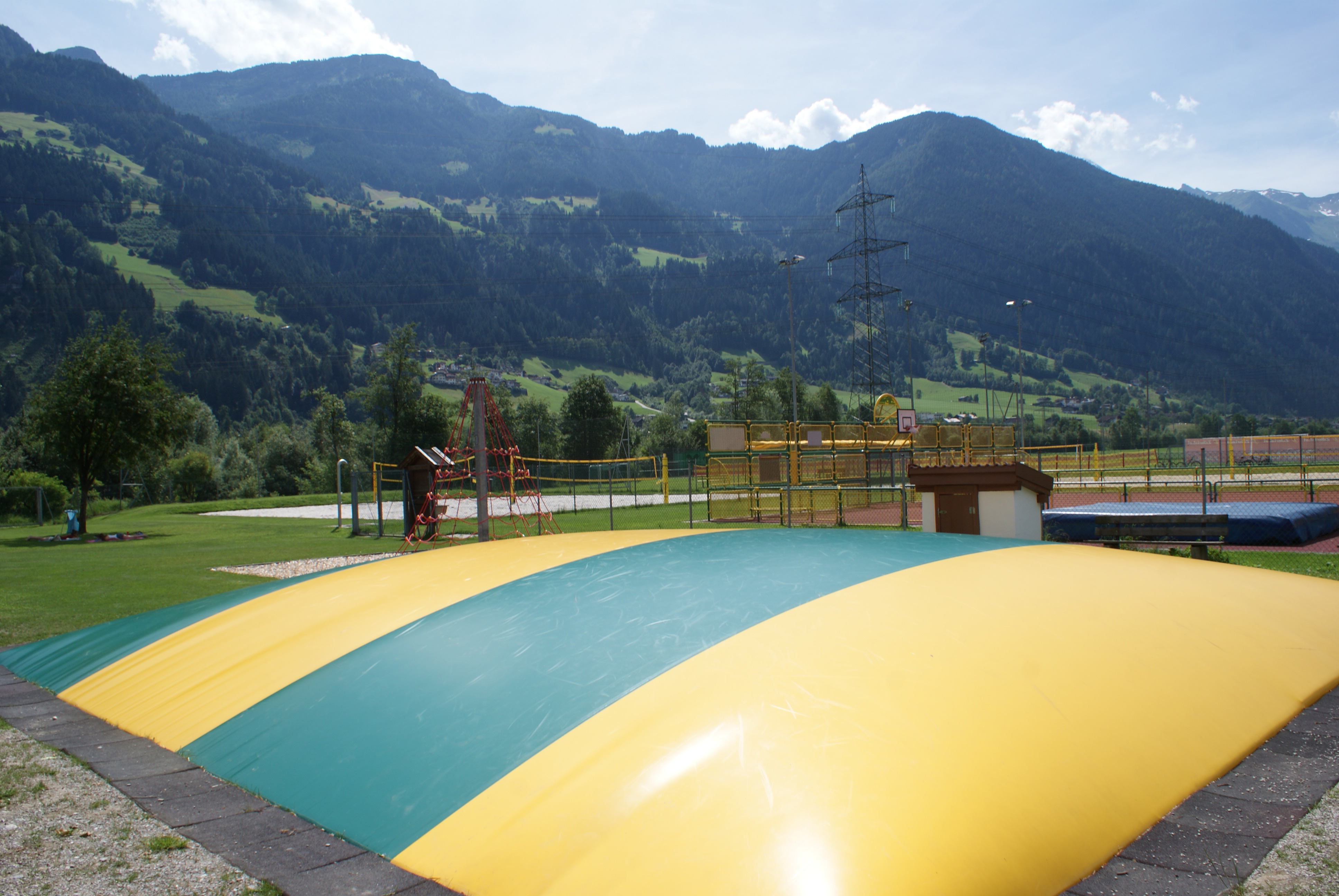 Large inflatable jumping bubble at Sommerwelt Hippach with mountain backdrop, a fun play attraction for children on a spacious green leisure area in Tyrol.