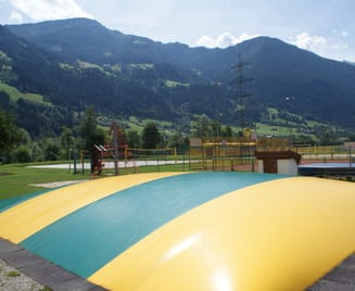 Große aufblasbare Hüpfbubble in der Sommerwelt Hippach vor Bergkulisse, Spielattraktion für Kinder auf einer weitläufigen, grünen Freizeitanlage in Tirol.