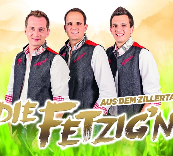 Drei junge Männer in Trachtenjacken vor buntem, fröhlichem Hintergrund, lächelnd für ein Gruppenfoto.