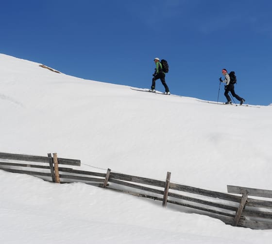 Two people walking in the snow on a ski tour