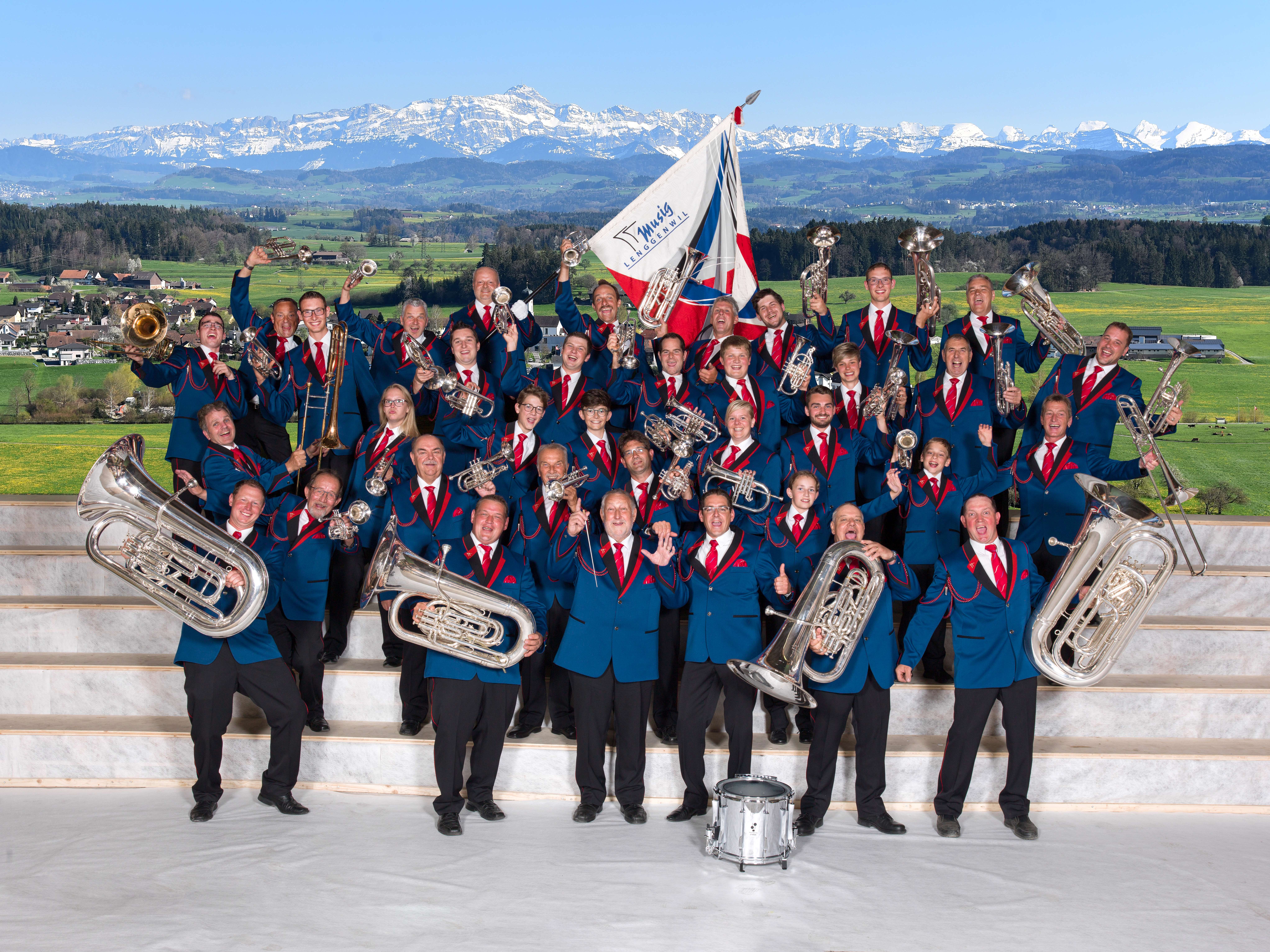 Das Bild zeigt ein Gruppenfoto der Musig Lenggenwil in blauen Trachten und Musikinstrumenten in der Hand.