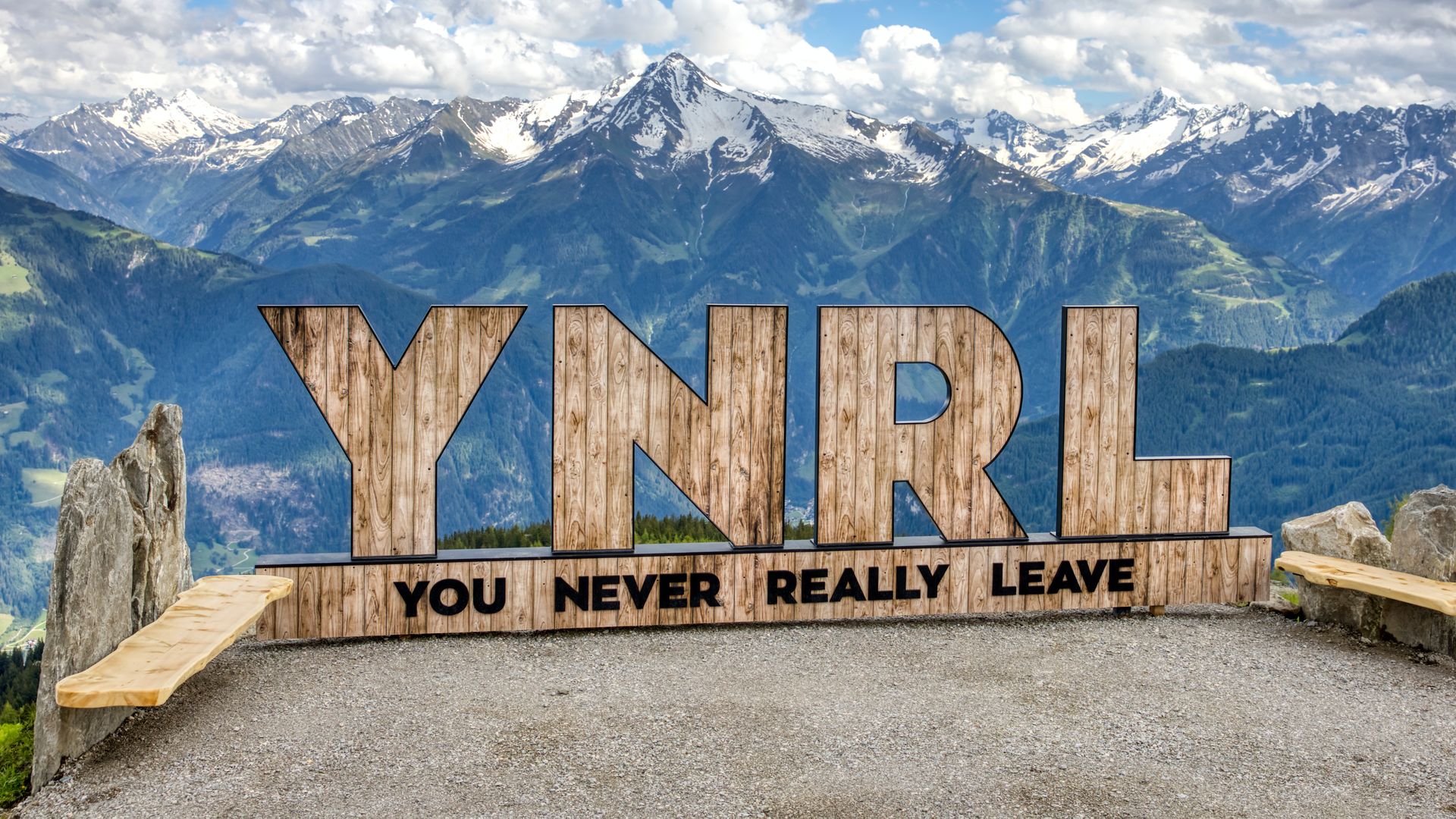 Holzskulptur YNRL vor Zillertaler Alpenpanorama als Einleitung zu den FAQs. Das Bild steht für bleibende Erinnerungen durch bestens informierte Urlaubsplanung in Mayrhofen-Hippach – von der Anreise bis zum Skipass.