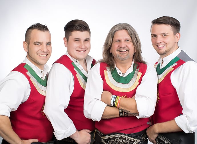 Fünf Männer in traditionellen Trachten, lächelnd, vor hellem Hintergrund, vermutlich die Freddy Pfister Band.