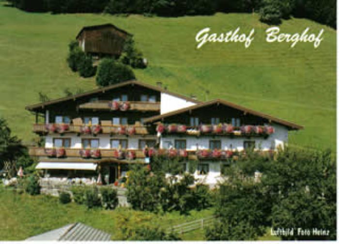 Das Bild zeigt den Gasthof Berghof von außen. Vor dem Gebäude erstreckt sich eine grüne Wiese, und ringsum stehen Bäume, die eine naturnahe und gemütliche Atmosphäre schaffen.