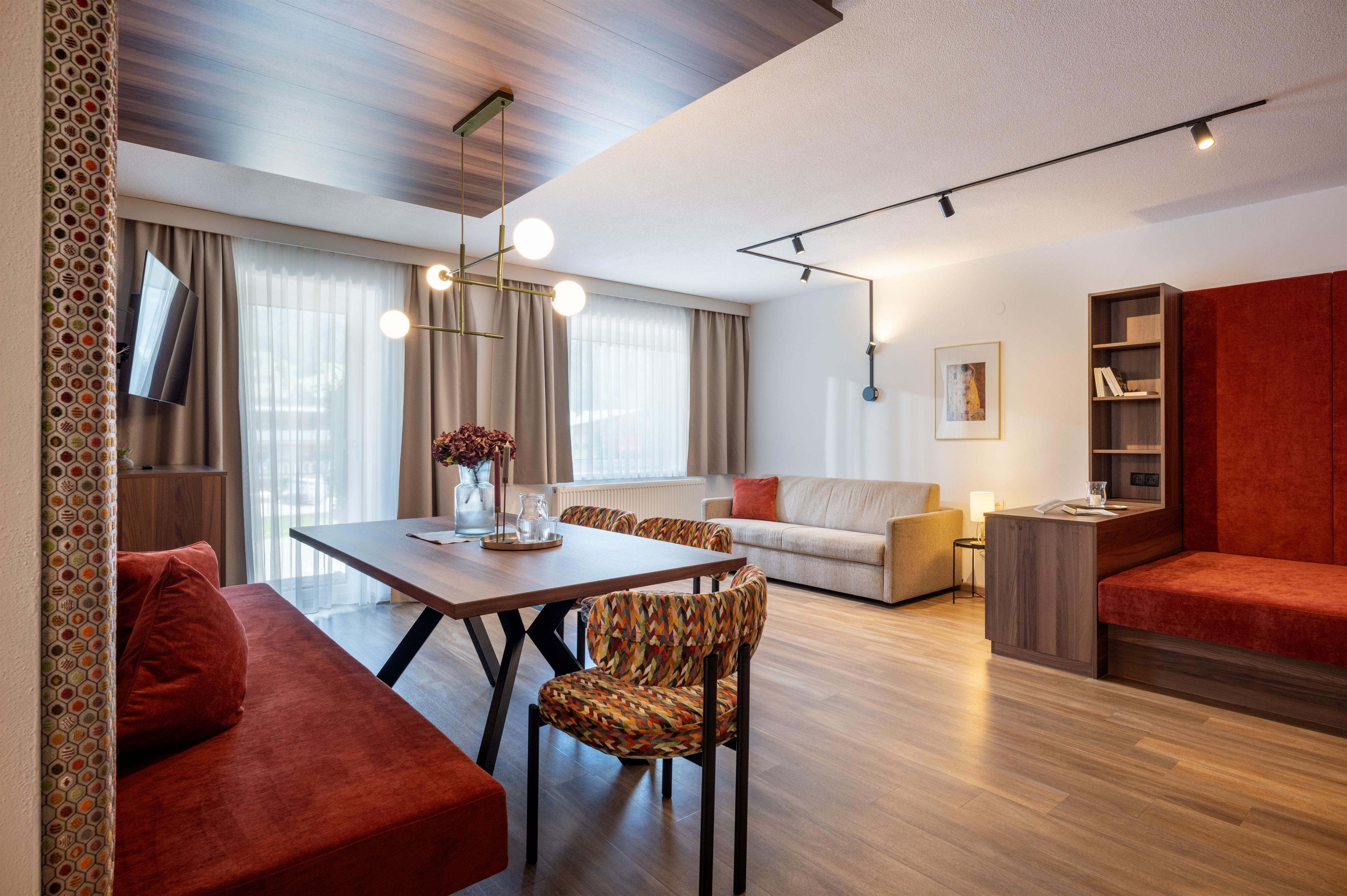 Modernes Wohnzimmer mit Sofa, Esstisch, Stühlen, großen Fenstern und dekorativen Lampen.