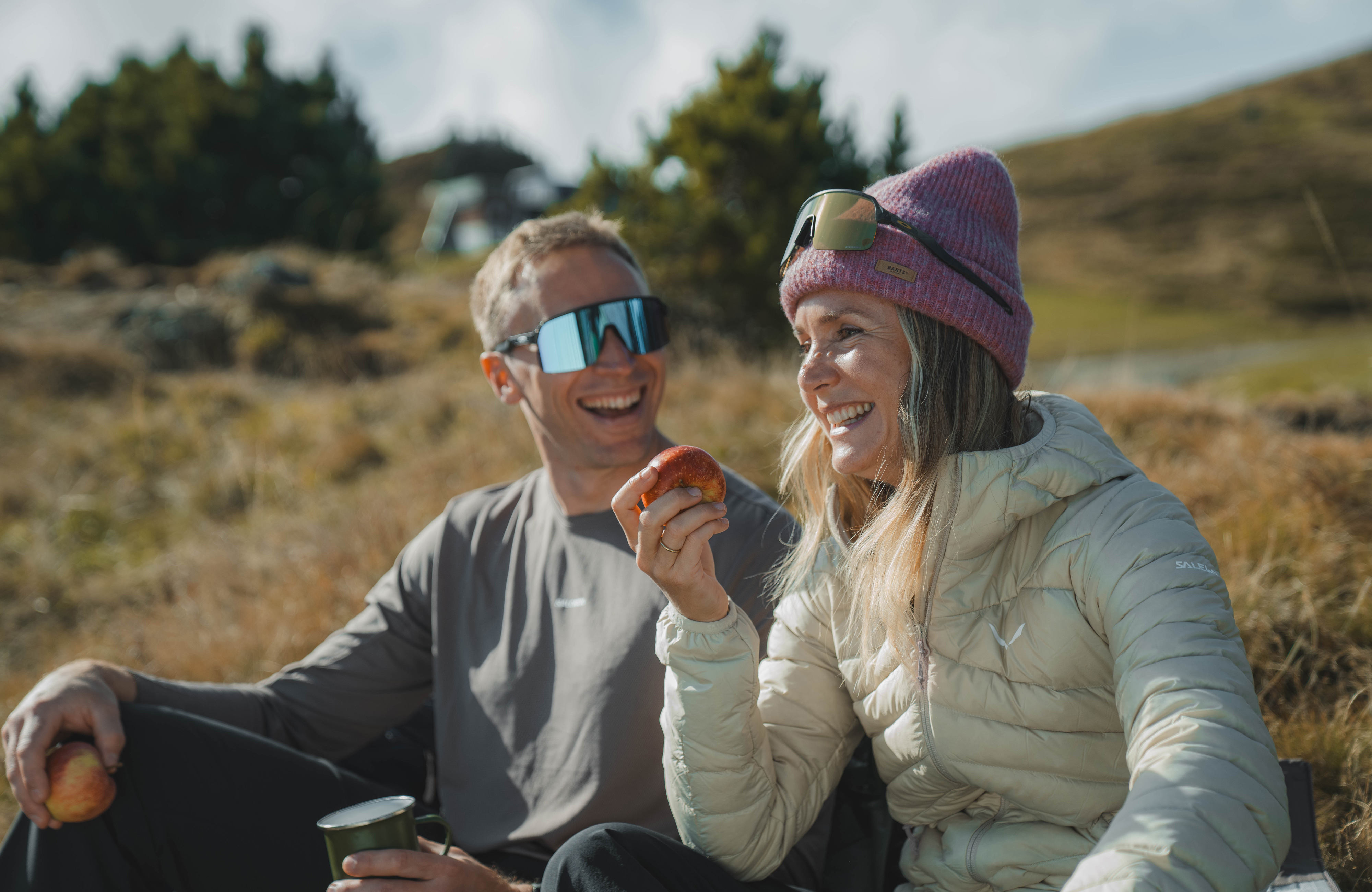 Herbstwanderung in Mayrhofen im Zillertal: Zwei Wanderer sitzen auf einer Almwiese, trinken aus Tassen und genießen die Sonne in der Berglandschaft.