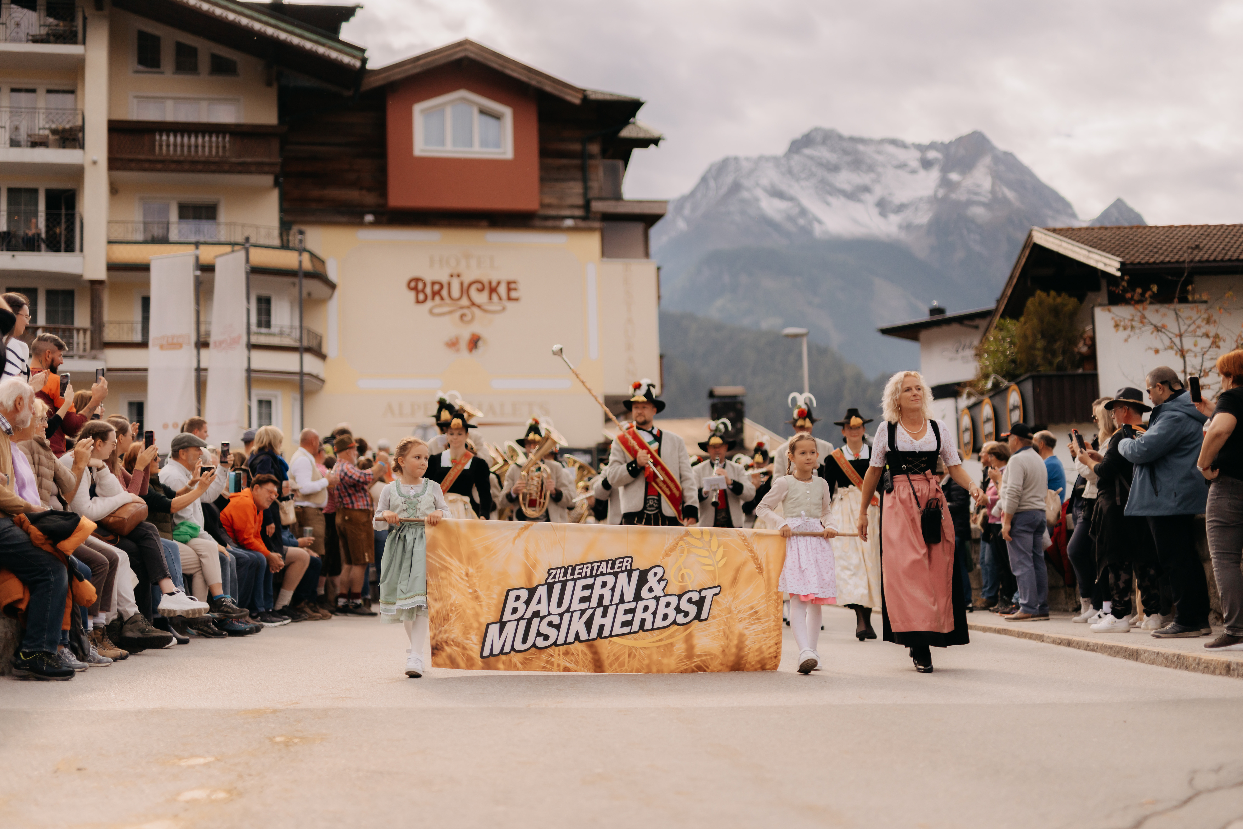 Brauchtumsumzug in Mayrhofen anlässlich des Zillertaler Bauern- und Musikherbstes, mit Trachtenträgern und Musikkapelle, die durch den Ort vor zahlreichen Zuschauern marschieren.