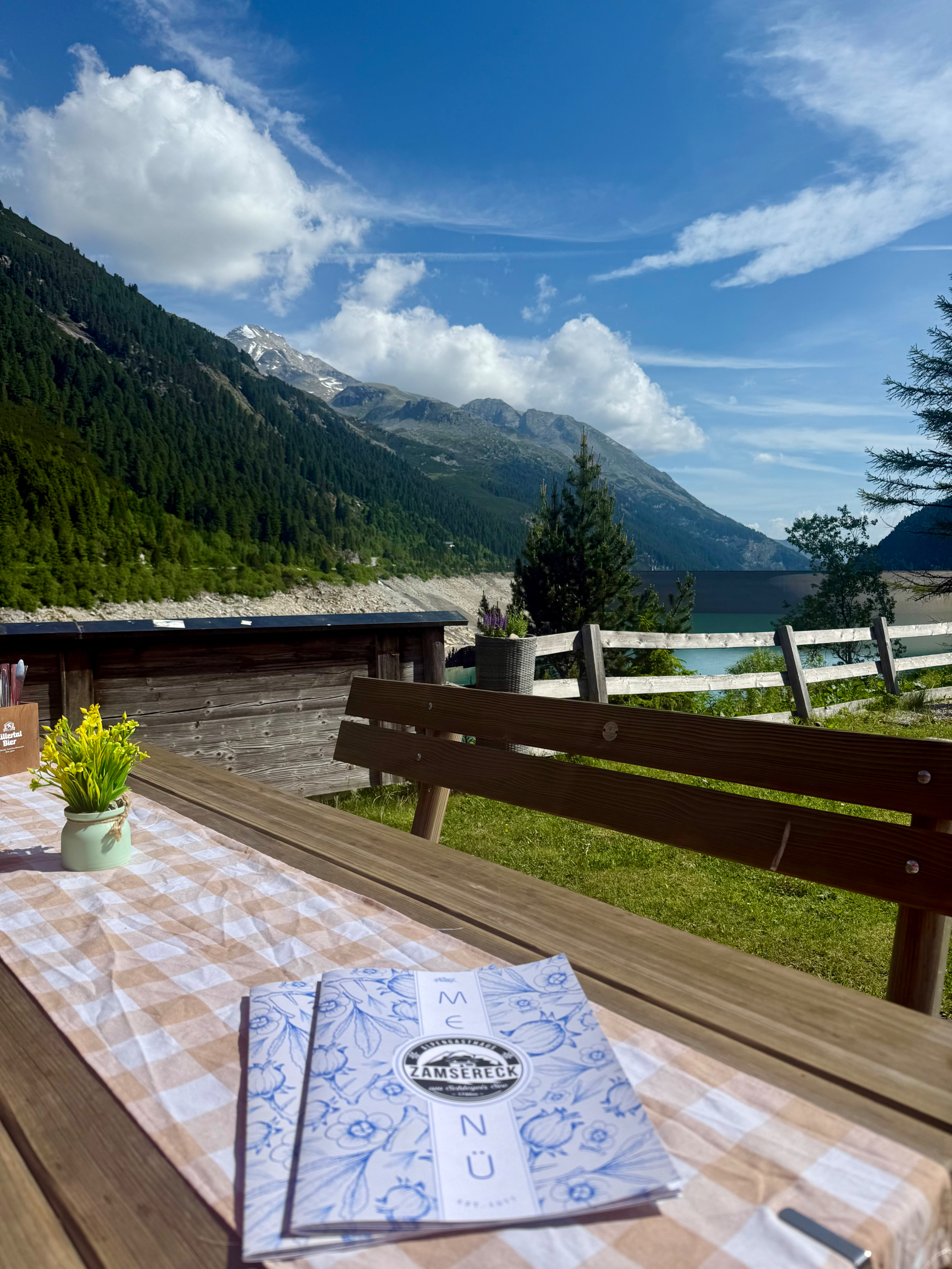 Bank mit Tisch und gedecktem Tisch sichtbar. Ausblick auf den Schlegeisstausee ist dargestellt