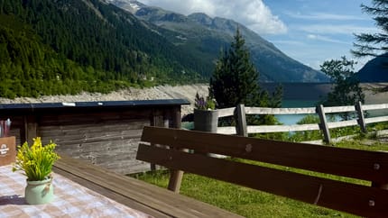 Bank mit Tisch und gedecktem Tisch sichtbar. Ausblick auf den Schlegeisstausee ist dargestellt