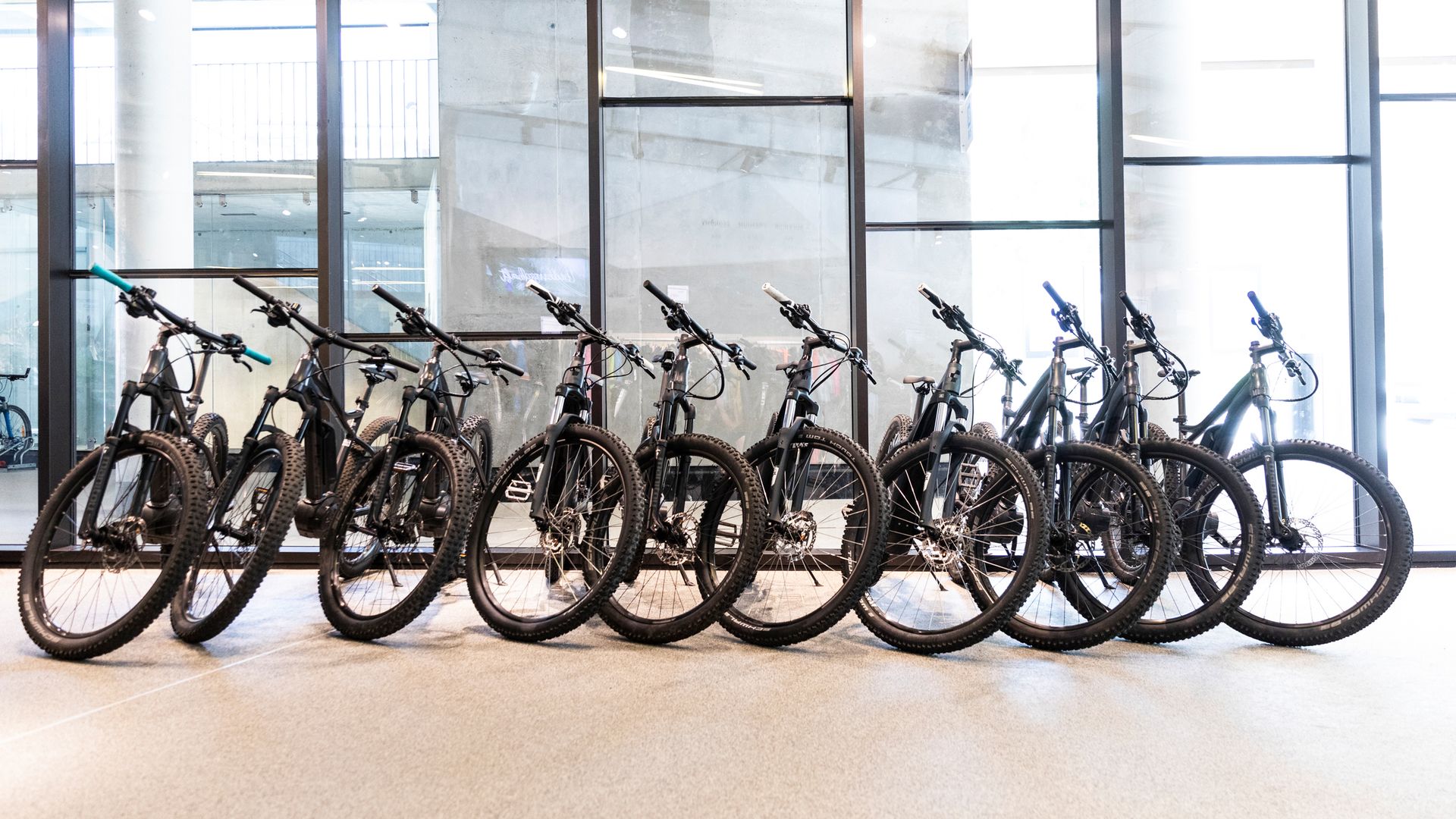 Row of modern bicycles and e-bikes in front of large glass windows – part of a bike rental in Mayrhofen-Hippach, Zillertal.