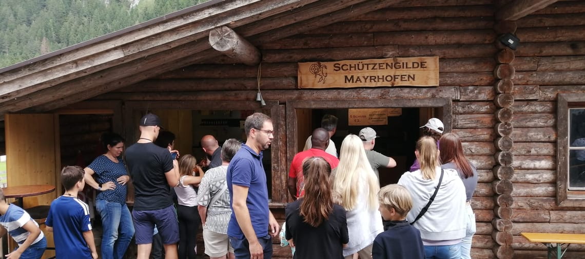 Das Bild zeigt die Schießbude der Schützengilde Mayrhofen mit Besuchern im Vordergrund.