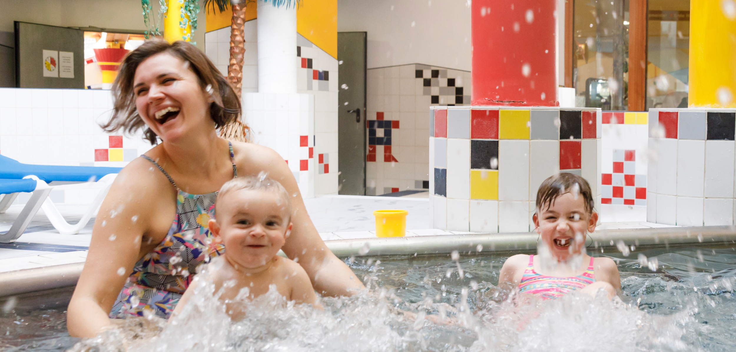 Mutter mit zwei kleinen Kindern beim Baden und Lachen im Erlebnis-Hallenbad Mayrhofen – familienfreundlicher Badespaß im Zillertal.