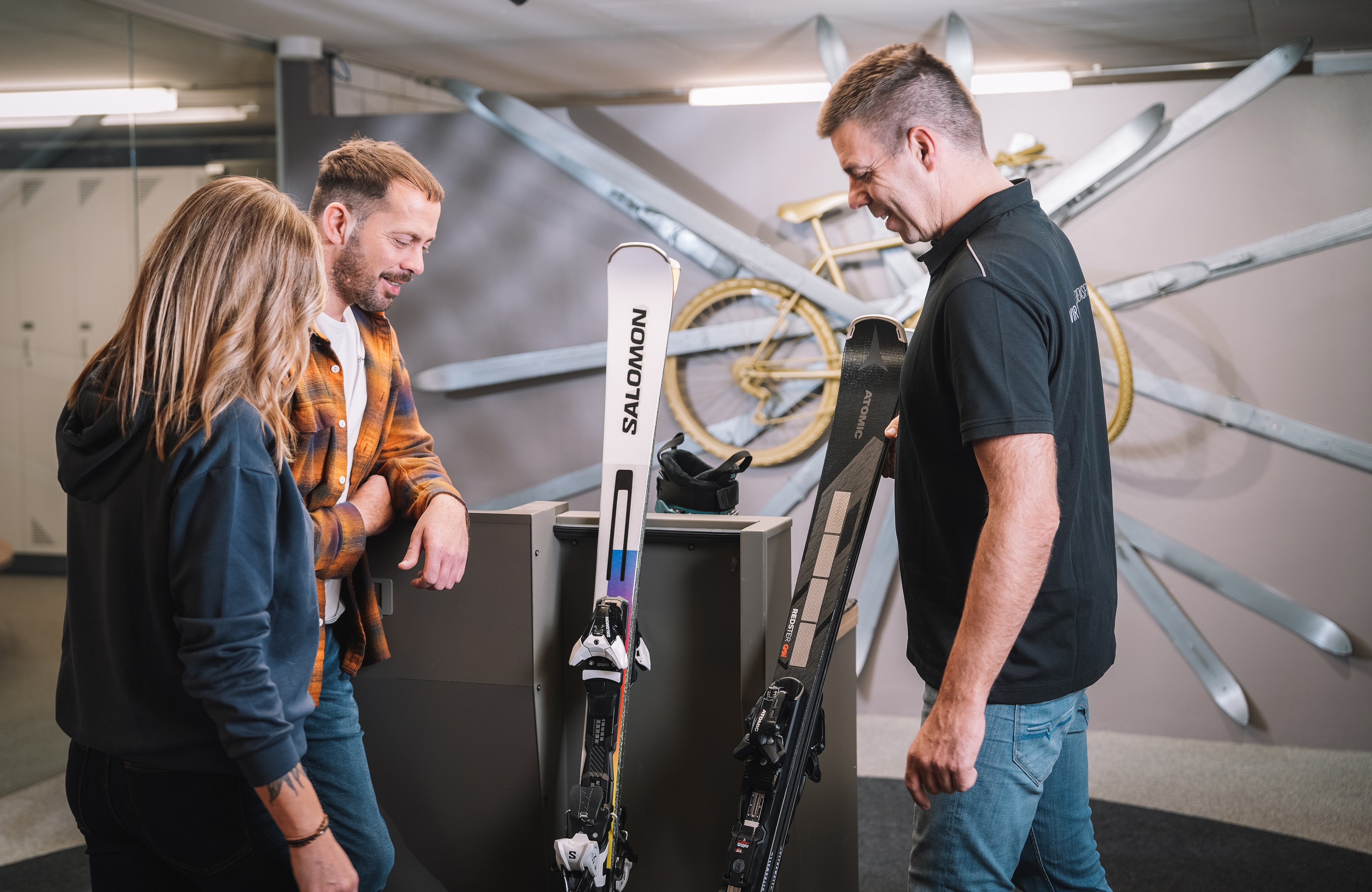 Skiverleih im Zillertal, Tirol: Mitarbeiter stellt am Servicegerät die Skibindung ein, während Gäste ihre Ausrüstung für den Winterurlaub in Mayrhofen-Hippach auswählen.